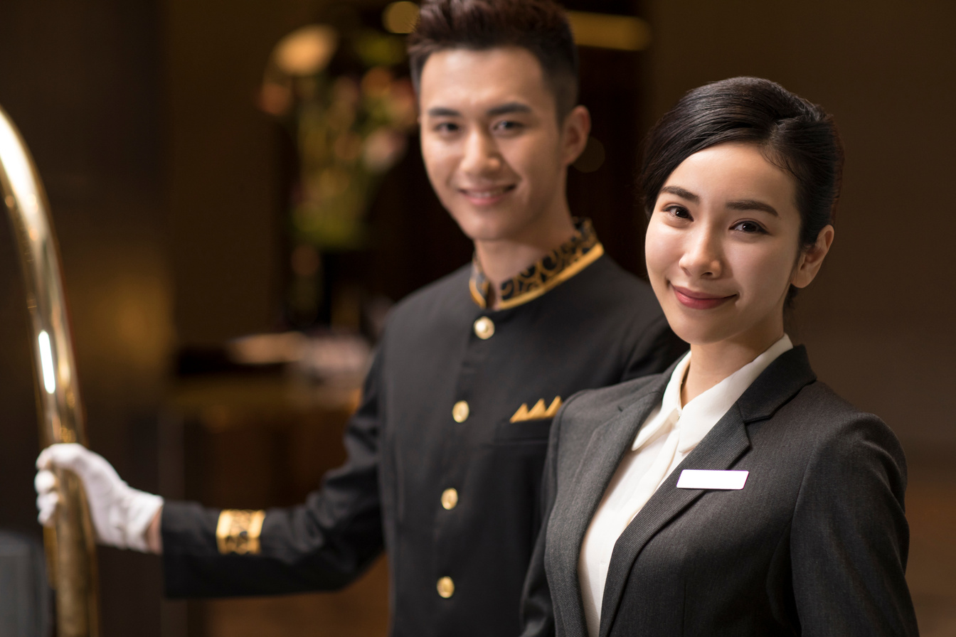 Smiling Chinese Male and Female Hotel Staff Standing in Hotel Lo